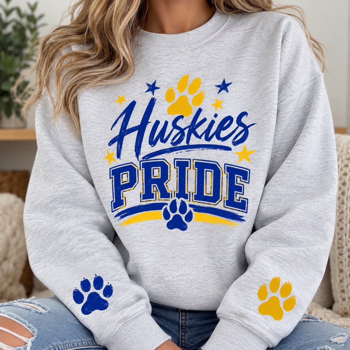 Huskies Pride ash crewneck with blue and gold chest design and sleeve paw prints